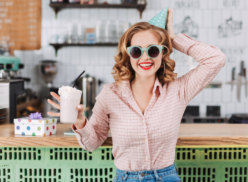 Frau steht in einer Bar mit einem Milchshake in der Hand